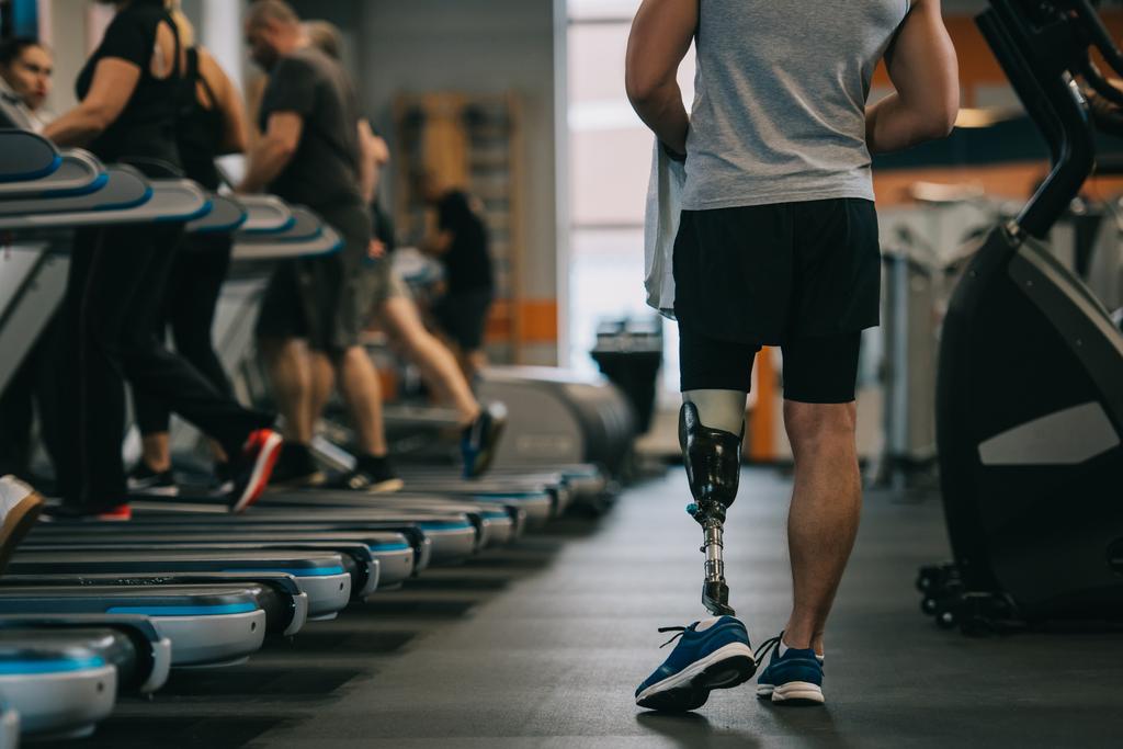 tiro recortado de deportista atlético con pierna artificial caminando por el gimnasio
 - Foto, imagen
