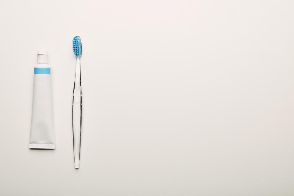 top view of toothbrush and toothpaste arranged on white backdrop, dentistry concept - Photo, Image