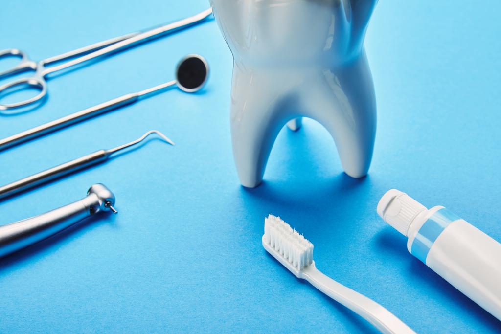 widok modelu białych zębów, szczoteczki do zębów, pasta do zębów i ze stali nierdzewnej instrumenty dentystyczne na niebieskim tle z bliska - Zdjęcie, obraz