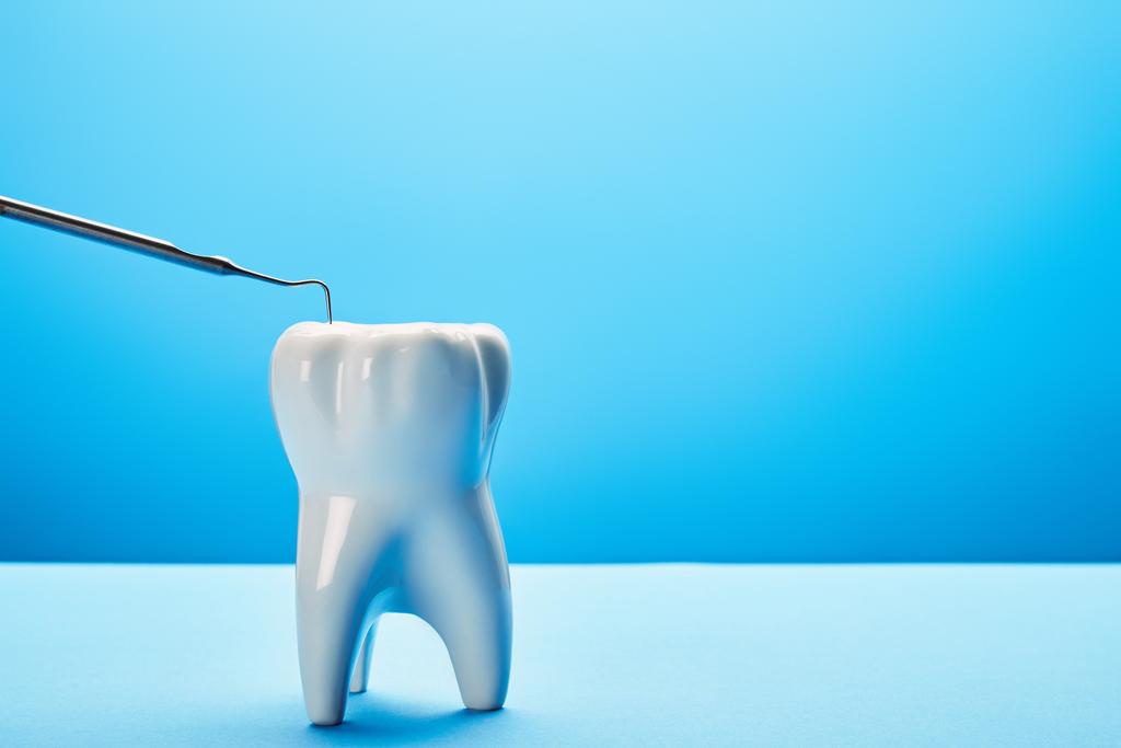 Nahaufnahme von Zahnmodell und Zahnsonde auf blauem Hintergrund - Foto, Bild
