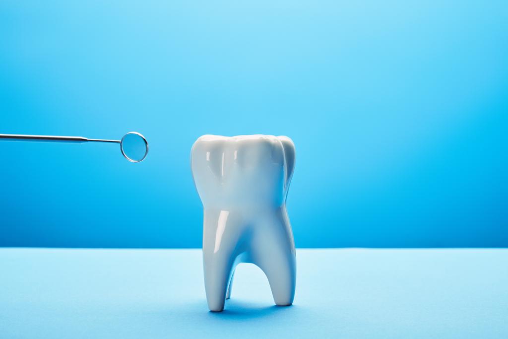 κλείνω πάνω θέα του μοντέλου των δοντιών και οδοντιατρική στόμα καθρέφτη σε μπλε φόντο - Φωτογραφία, εικόνα