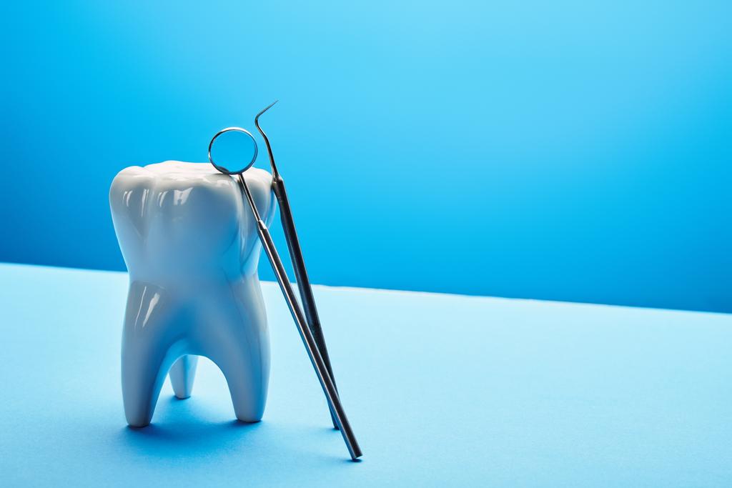 Nahaufnahme von Zahnmodell, Zahnspiegel und Sonde auf blauem Hintergrund - Foto, Bild