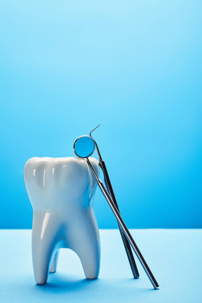 Close-up van tand model, tandheelkundige spiegel en sonde op blauwe achtergrond - Foto, afbeelding