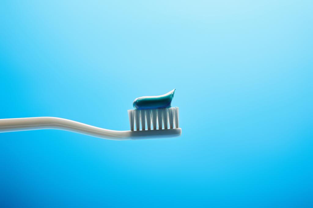 vista de perto da escova de dentes com pasta no fundo azul
 - Foto, Imagem