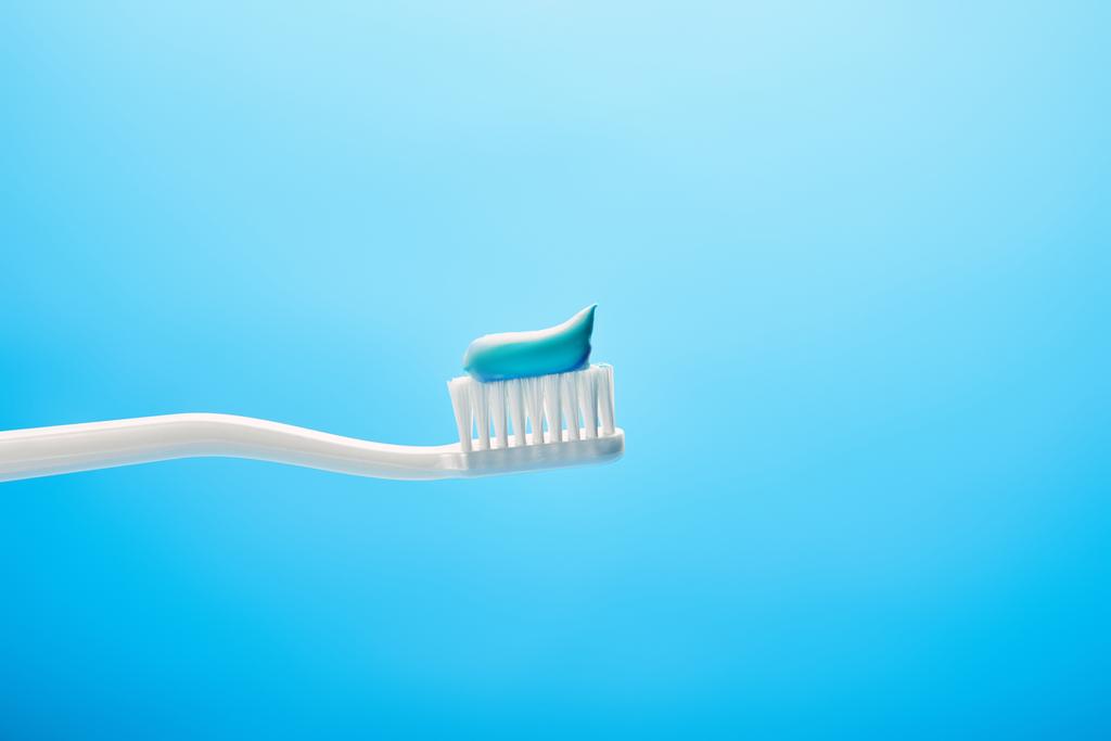vista de cerca del cepillo de dientes con pasta sobre fondo azul
 - Foto, Imagen