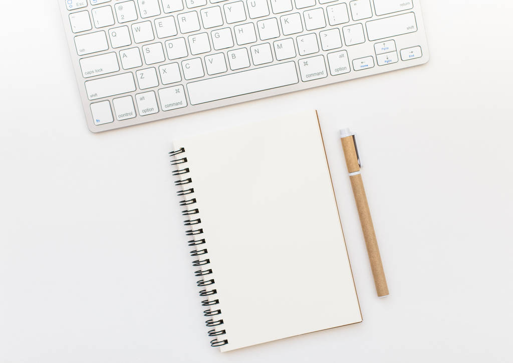 Cuaderno en blanco, pluma y teclado sobre fondo blanco. Espacio del bloc de notas para la entrada de texto
 - Foto, imagen