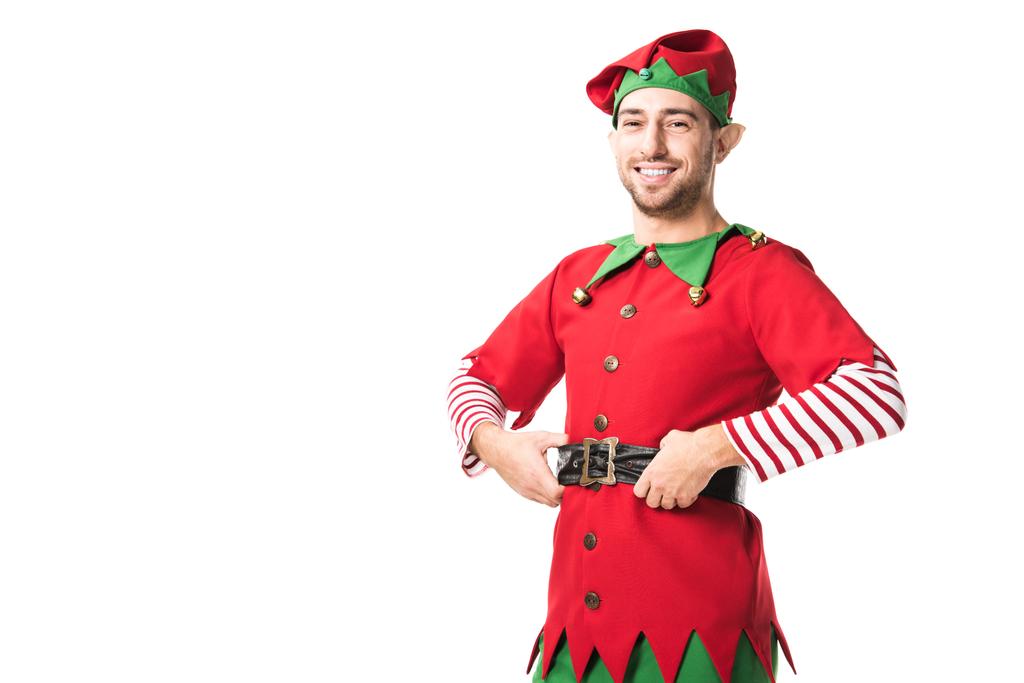 neşeli Noel elf kostümü kameraya ellerle kalça üzerinde beyaz izole seyir erkekte - Fotoğraf, Görsel