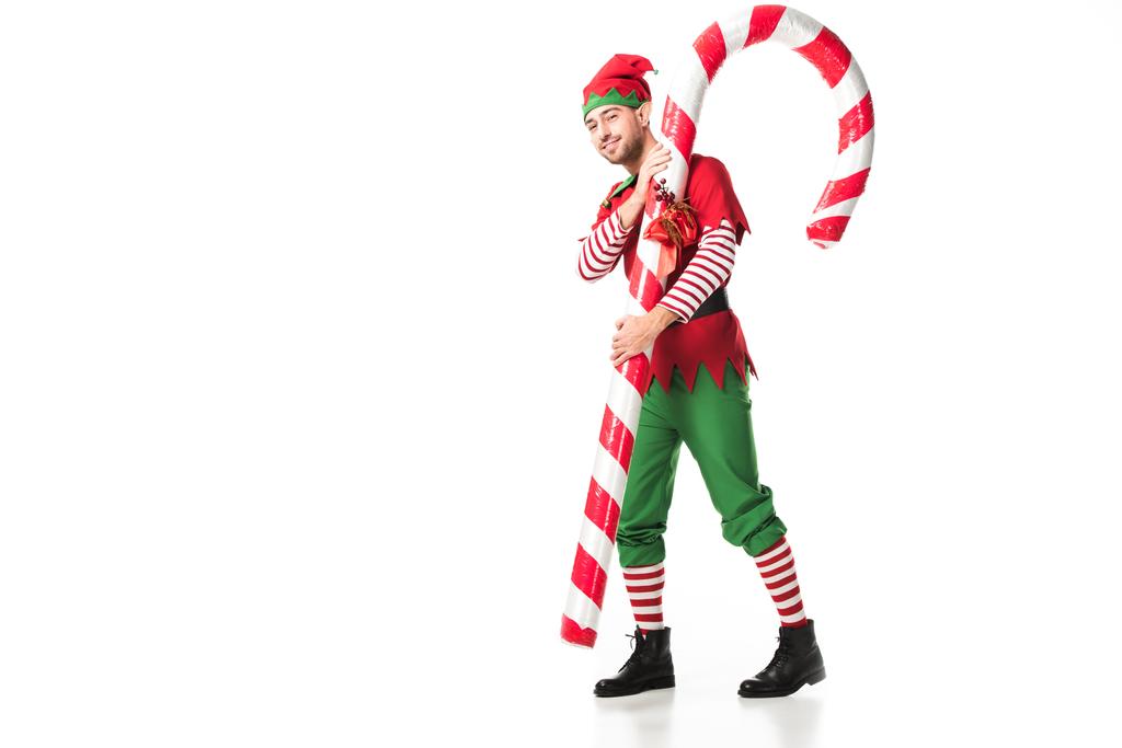 hombre en traje de elfo de Navidad llevando gran bastón de caramelo aislado en blanco
 - Foto, Imagen