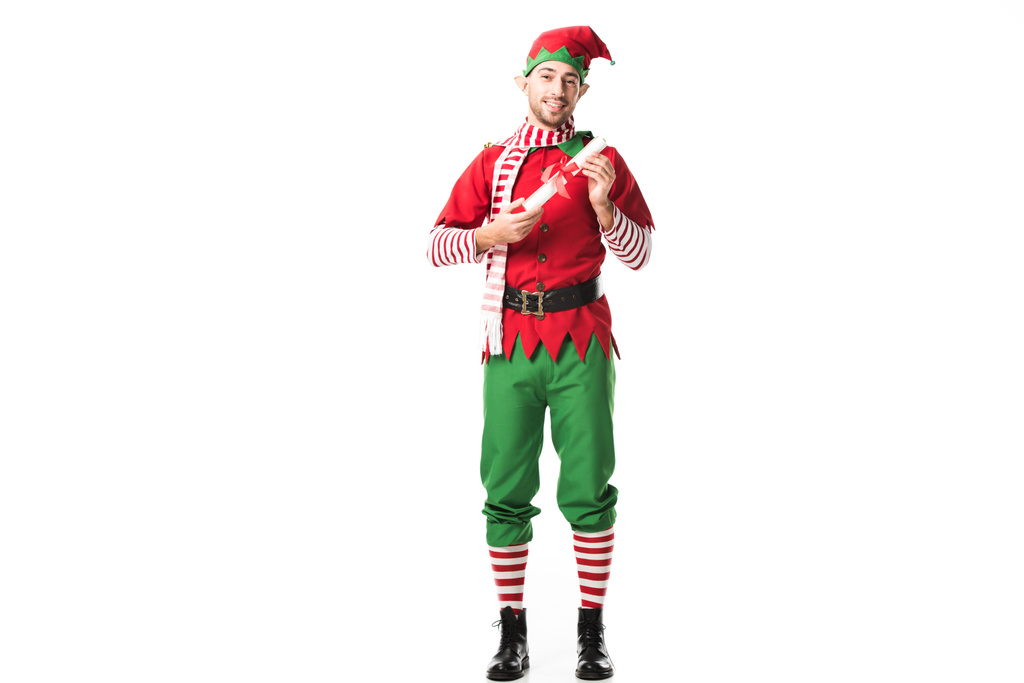 クリスマス エルフ衣装ウィッシュ リスト ロールを押しながら白で隔離カメラ目線で笑顔の男 - 写真・画像