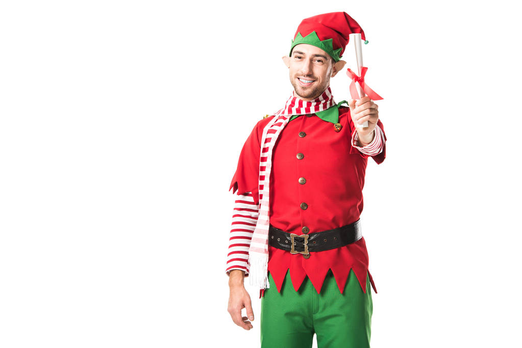 Улыбающийся мужчина в рождественском костюме эльфа держит рулон вишлиста и смотрит на камеру, изолированную на белом
 - Фото, изображение