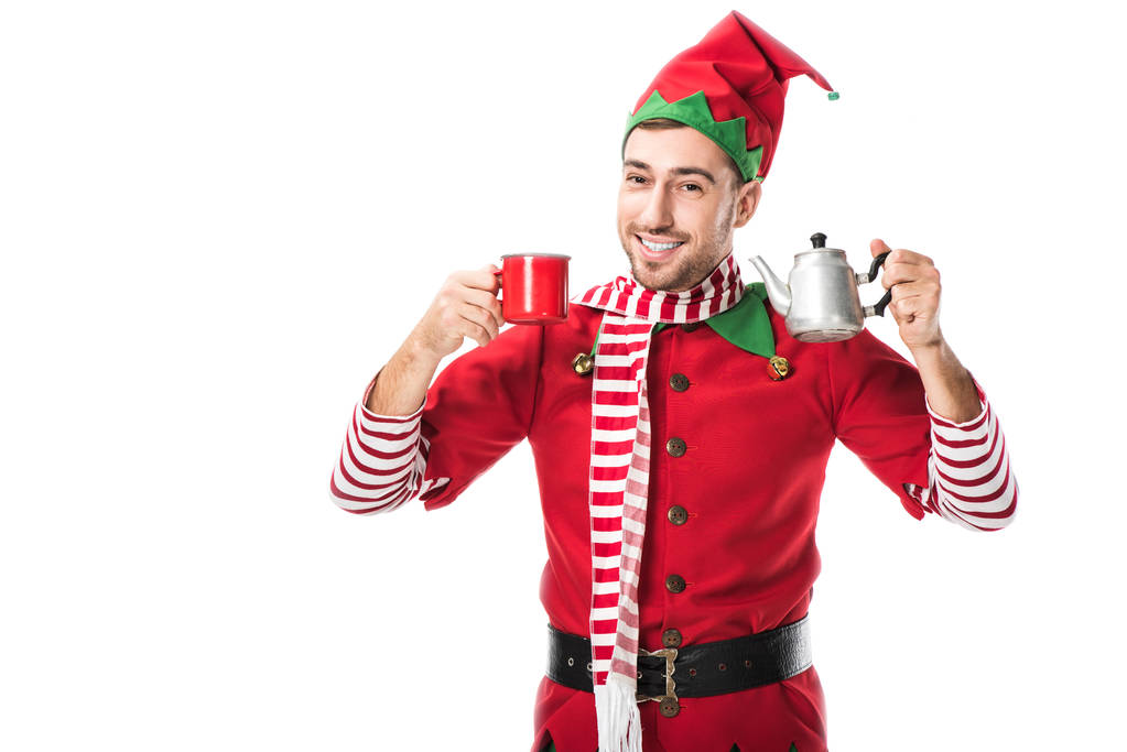 happy man in christmas elf costume holding red cup and metal kettle isolated on white - Photo, Image