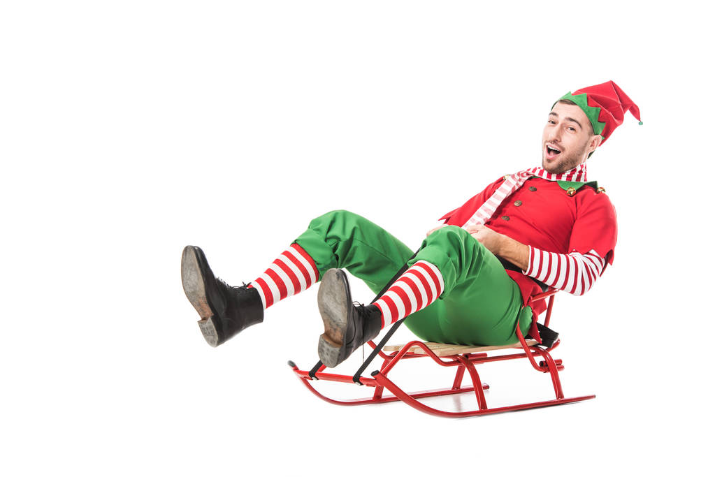 cheerful excited man in christmas elf costume riding sleigh isolated on white background - Photo, Image