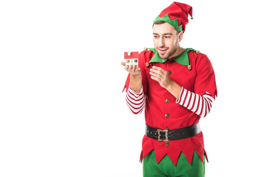 szczęśliwy człowiek, w Boże Narodzenie elf kostium gospodarstwa dom model na białym tle na biały, sprzedaż nieruchomości i ubezpieczeń koncepcja - Zdjęcie, obraz