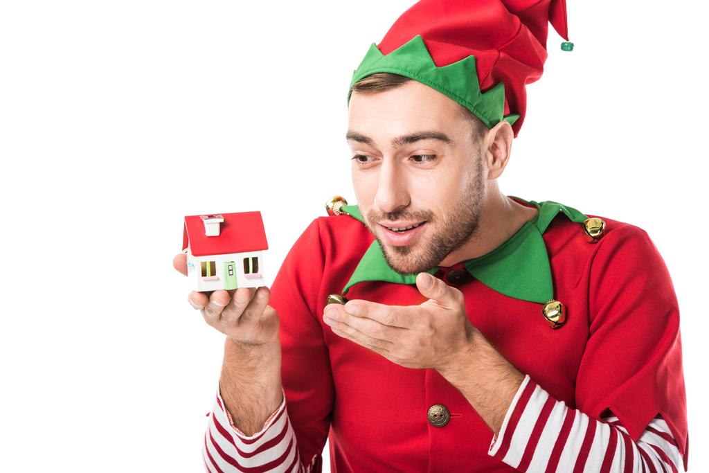homme en costume d'elfe de Noël pointant vers la maison modèle isolé sur blanc, vente immobilière et concept d'assurance
 - Photo, image