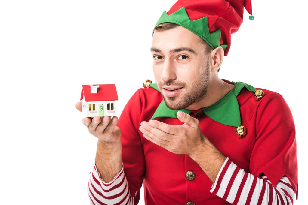 man in christmas elf costume pointing at house model isolated on white, real estate sale and insurance concept - Photo, Image