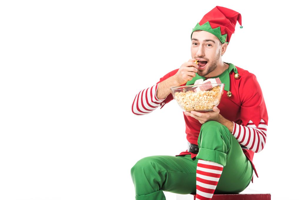 クリスマス エルフの衣装はポップコーンを食べると白で隔離カメラ目線の男 - 写真・画像