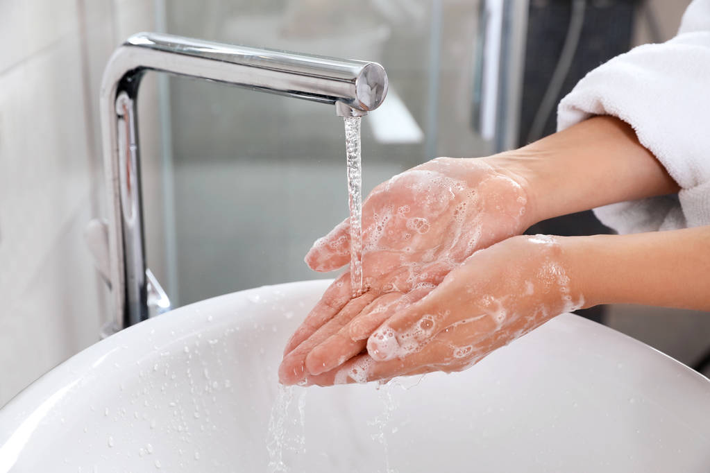 Mujer lavándose las manos con jabón sobre el lavabo en el baño, primer plano
 - Foto, imagen