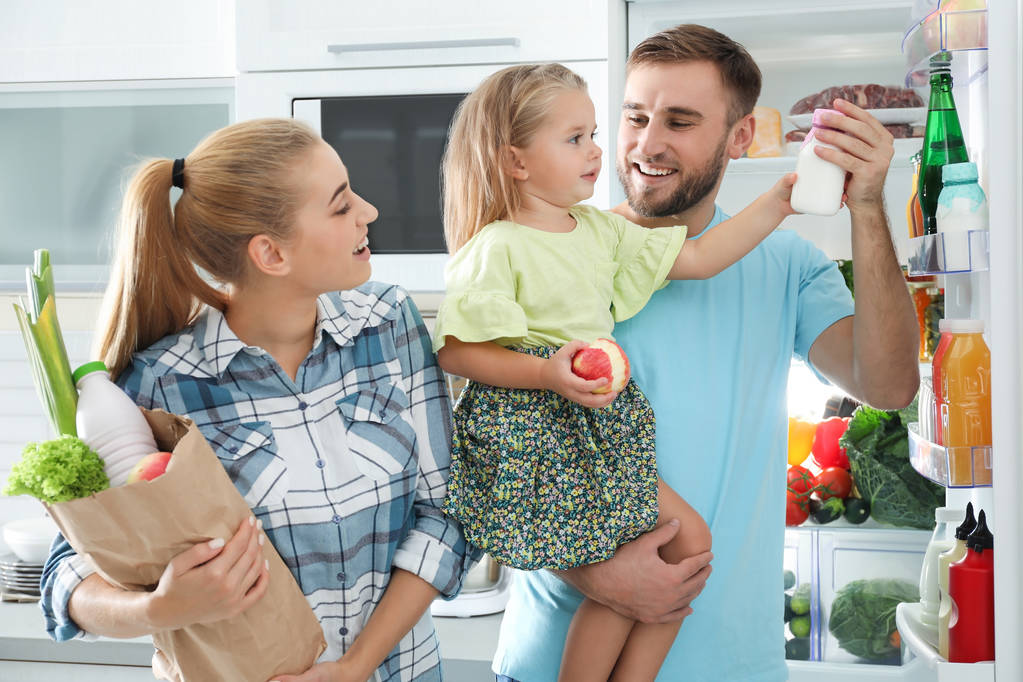Familia feliz con productos cerca del refrigerador en la cocina
 - Foto, imagen