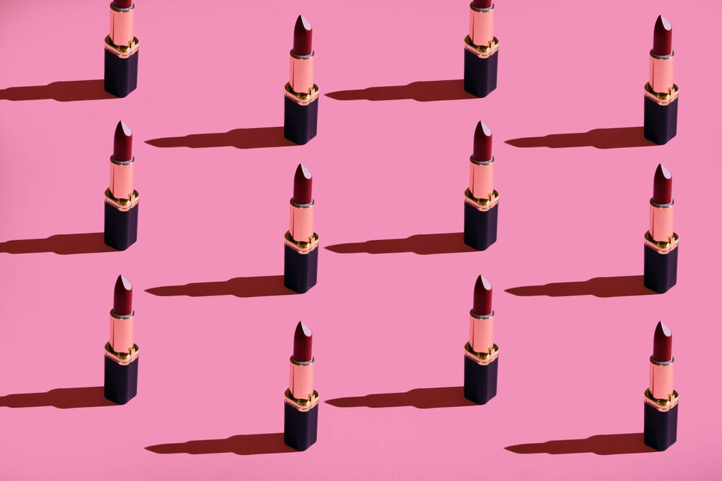 a lot of lipstick on a pink background hard light - Photo, Image