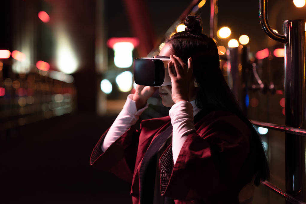 atractivo asiático chica usando virtual realidad auriculares en la calle en la noche, ciudad de futuro concepto
 - Foto, imagen