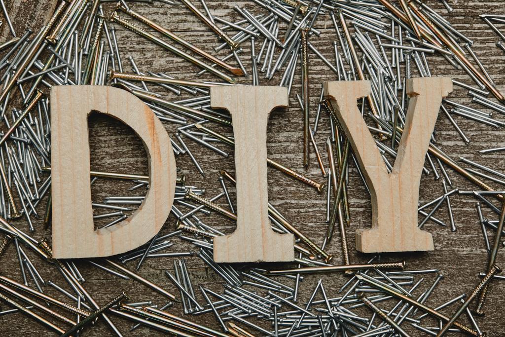 Top view of wooden diy sign and various nails tools on wooden table - Photo, Image