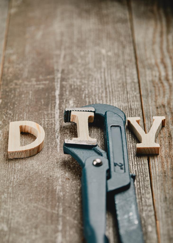 Close up of wooden diy sign and part of pipe wrench on wooden background - Photo, Image