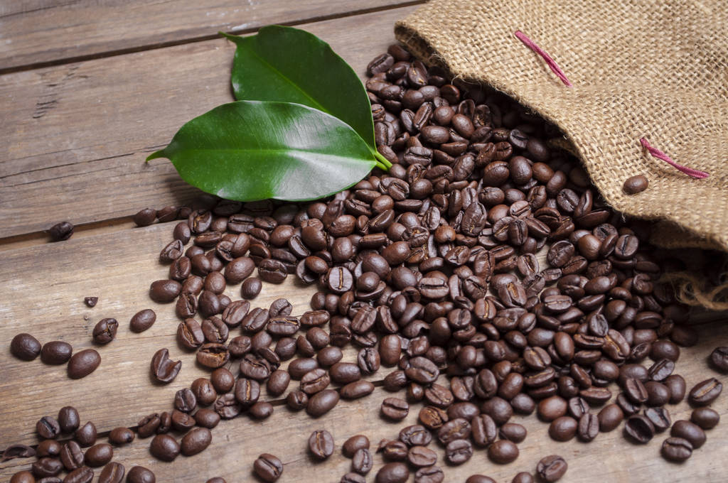 Tafel mit Kaffeebohnen und einer Tasse Kaffee auf natürlichem braunem Holz - Foto, Bild