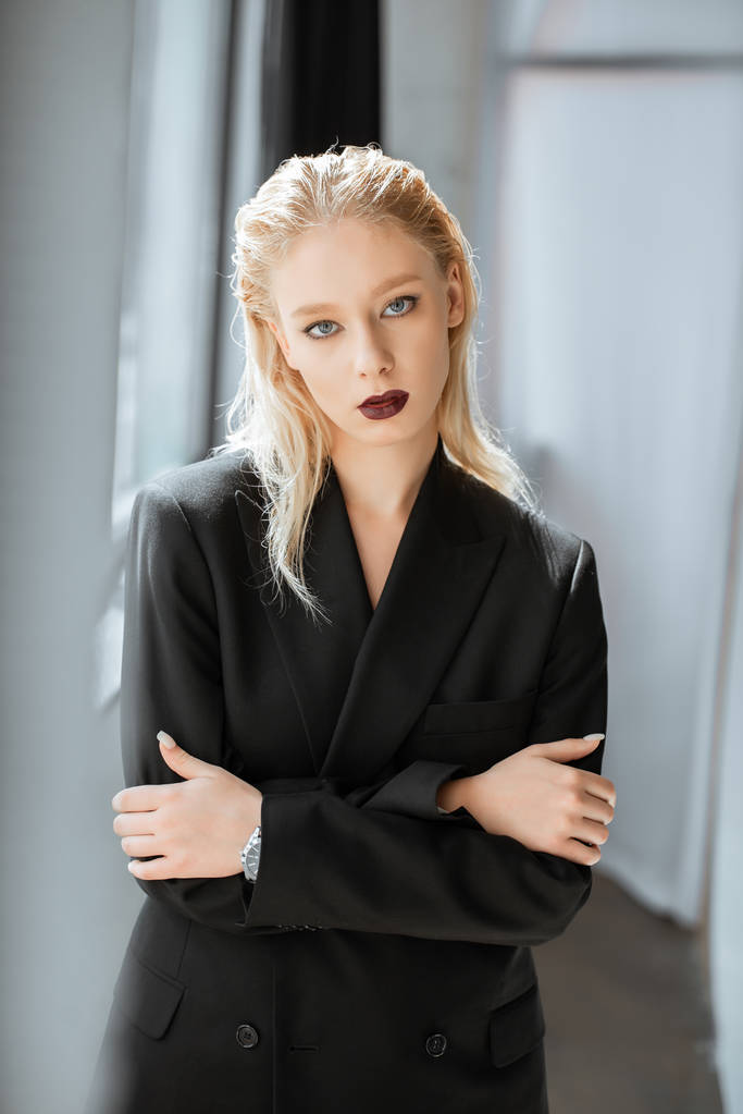 элегантная блондинка в модном черном костюме, позирующая на сером
 - Фото, изображение