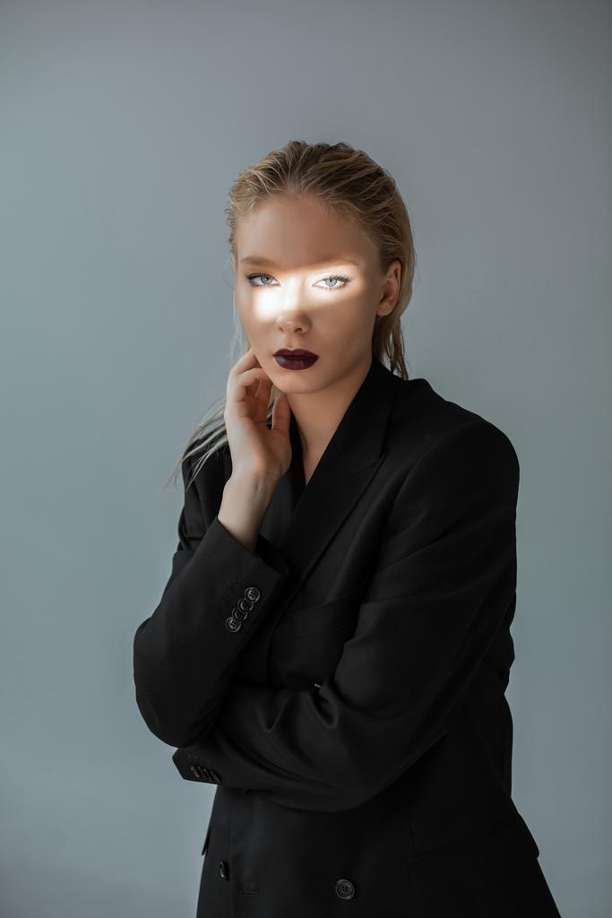 fashionable girl posing in formal wear with light beam on face isolated on grey - Photo, Image