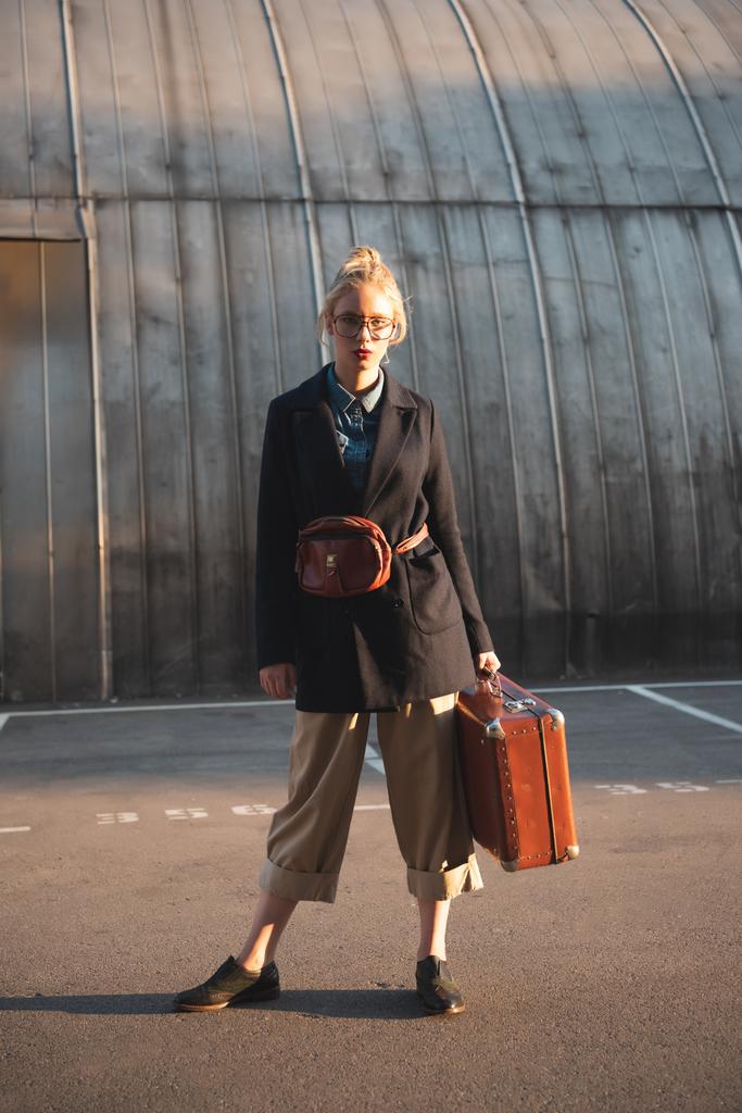 都市駐車場のレトロなスーツケースを持ってファッショナブルなエレガントな女の子 - 写真・画像