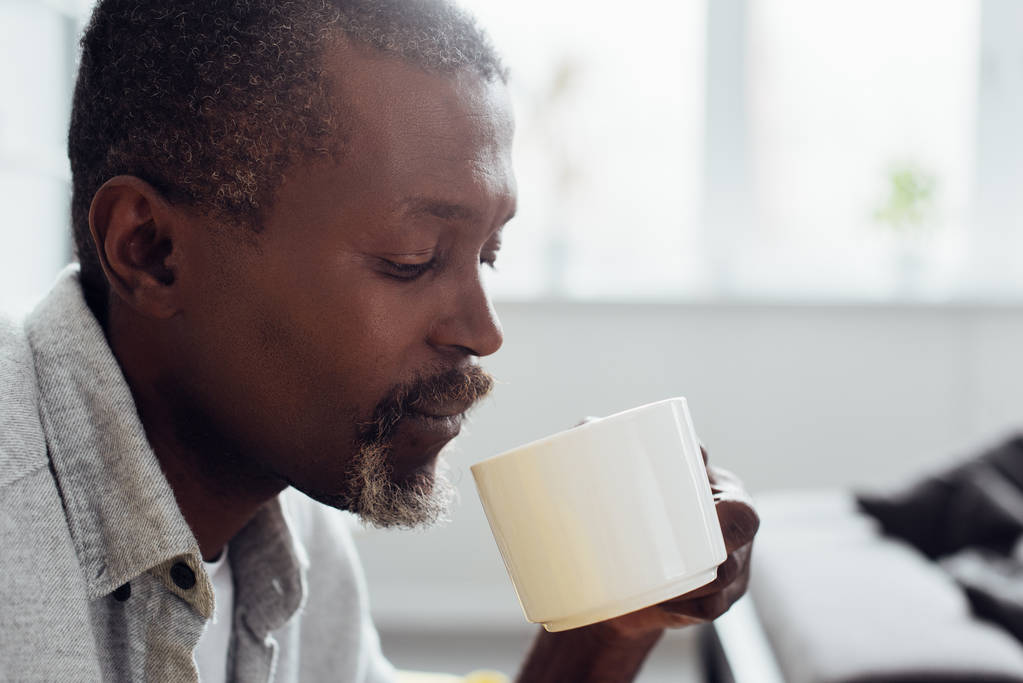 close up of mature african american man drinking coffee in living room  - Photo, Image