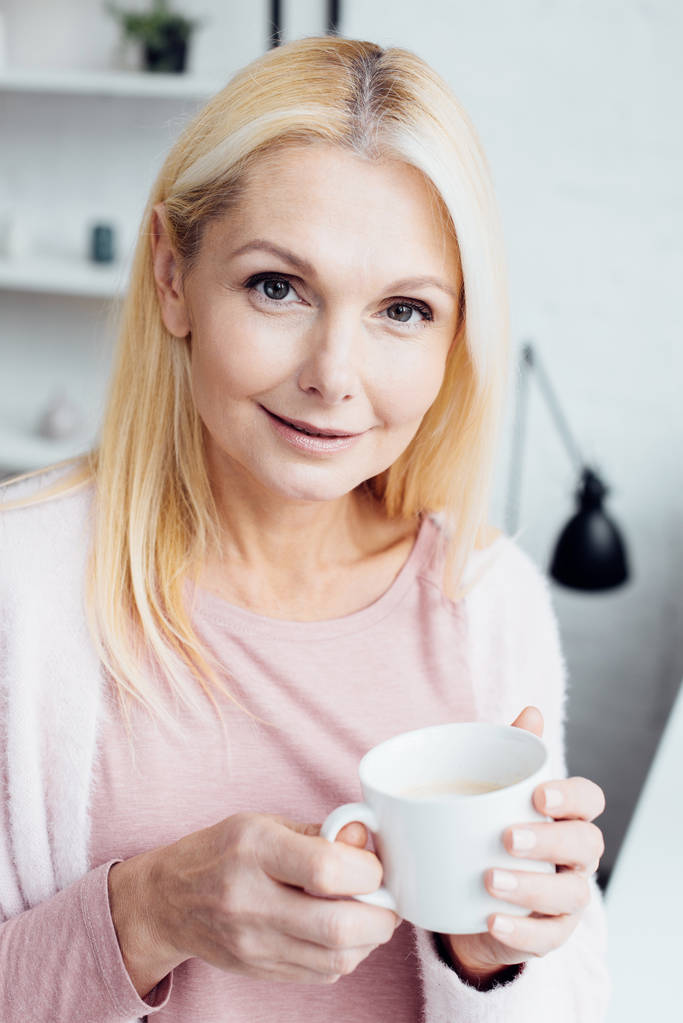 kaunis kypsä blondi nainen tilalla valkoinen kahvi kuppi
 - Valokuva, kuva