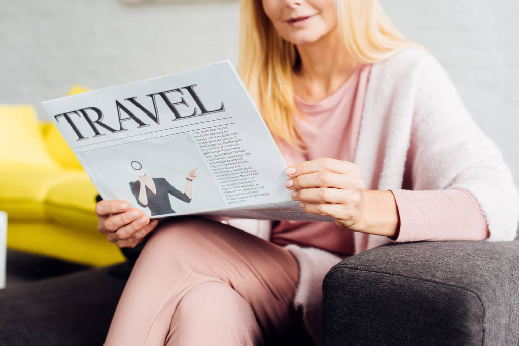 primer plano de la mujer madura sentada en el sofá y leyendo el periódico de viajes
  - Foto, imagen