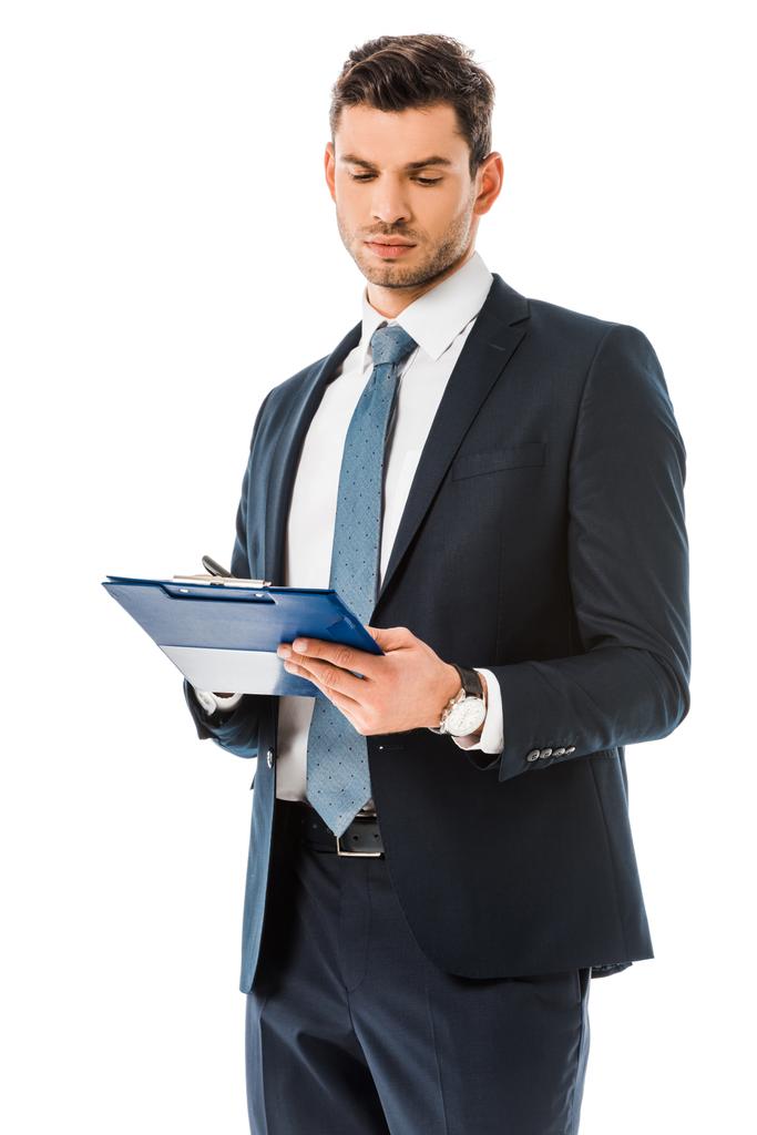Konzentrierter Geschäftsmann im Anzug blickt auf Klemmbrett isoliert auf Weiß  - Foto, Bild