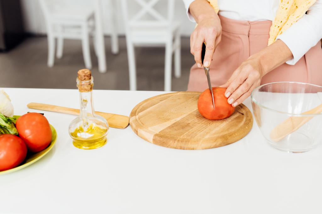 primer plano de las manos femeninas cortar el tomate en la tabla de cortar
 - Foto, imagen
