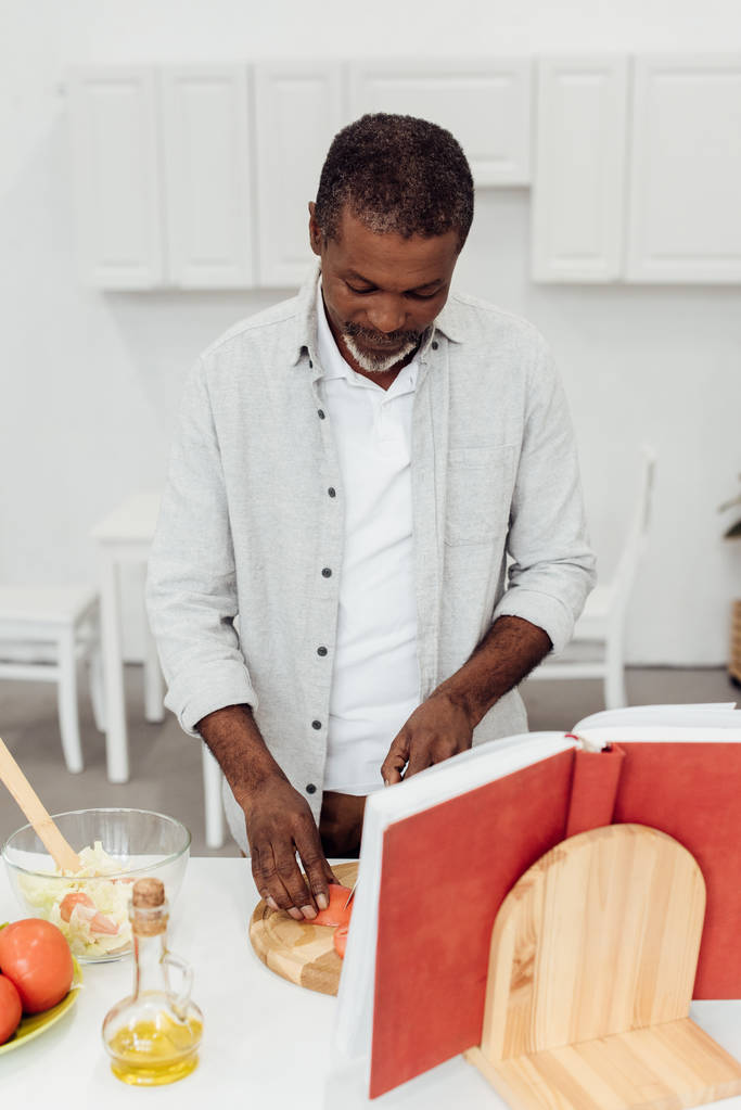 Afrika kökenli Amerikalı adam yemek kitabı mutfak at ile salata - Fotoğraf, Görsel