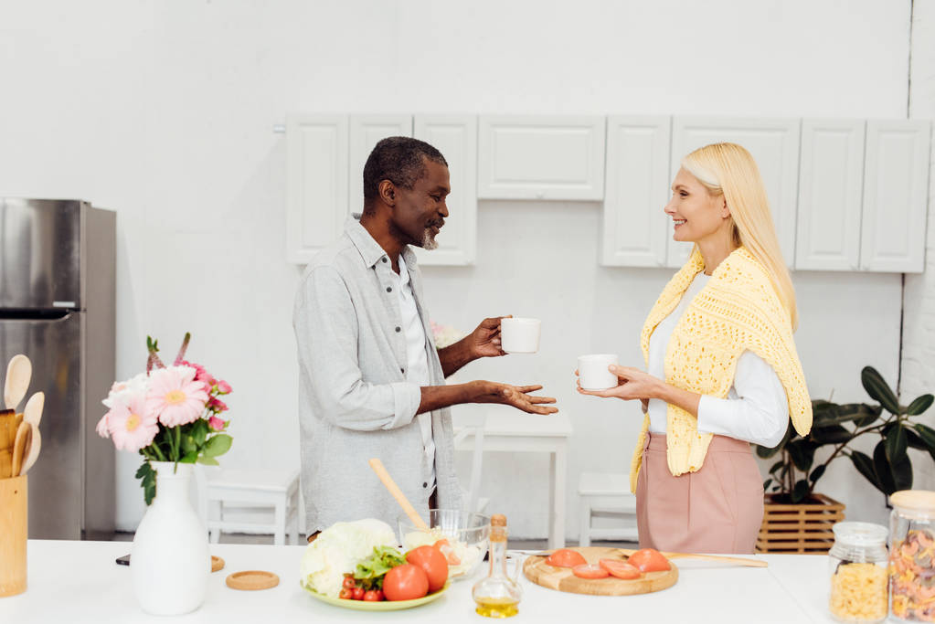 maduro rubia mujer y africano americano hombre beber café juntos en cocina
 - Foto, Imagen