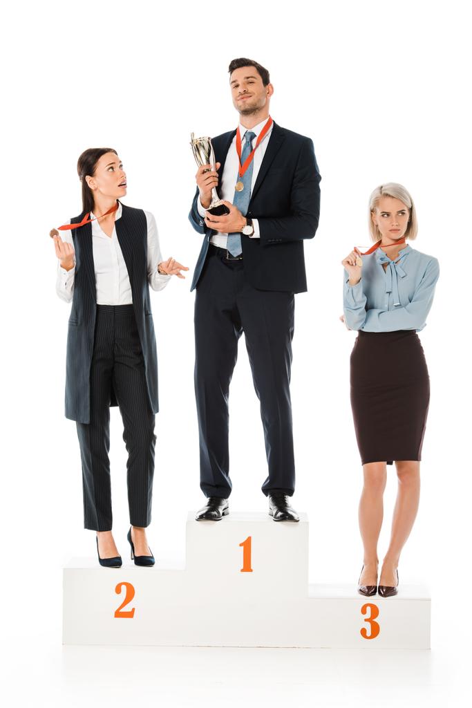 επιχειρηματίες που κατέχουν βραβεία ενώ στέκεται στο βάθρο νικητών που απομονώνονται σε λευκό - Φωτογραφία, εικόνα