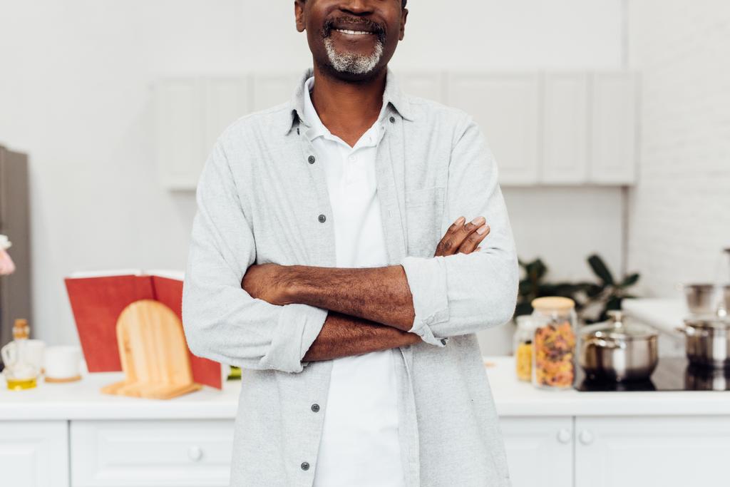 vue recadrée de l'homme afro-américain avec les bras croisés debout à la cuisine
 - Photo, image