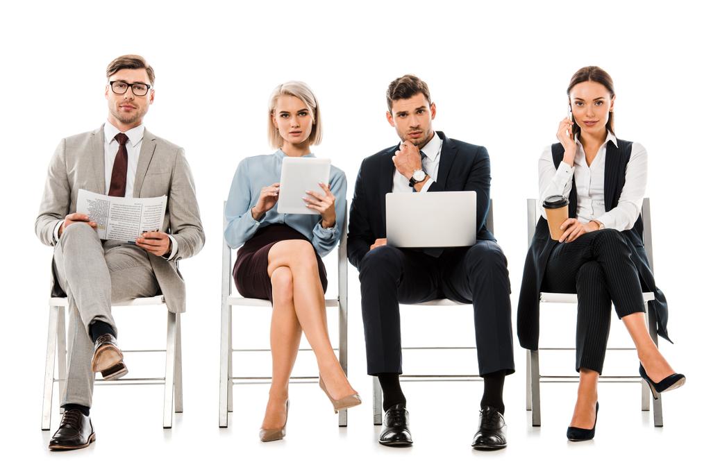 femmes d'affaires et hommes d'affaires assis sur des chaises avec gadgets, journal et café à emporter, isolés sur blanc
 - Photo, image