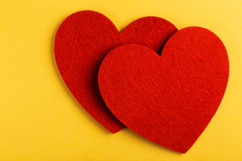 Дві червоні повстяні серце на яскраво-жовтому тлі. День Святого Валентина. Копія простір - Фото, зображення