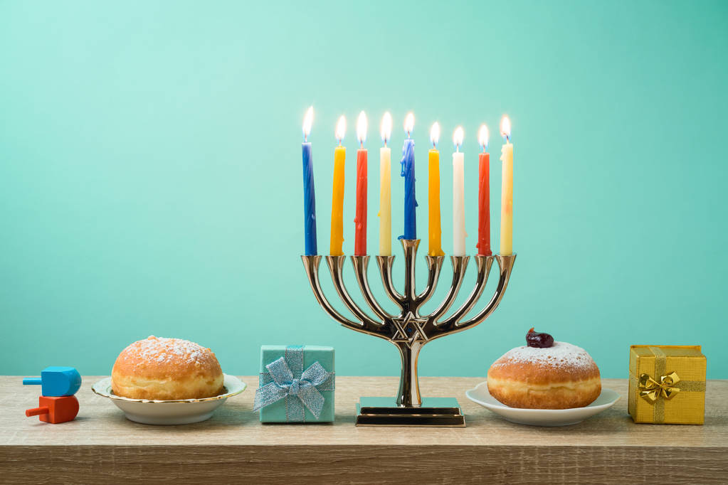 Židovský svátek Chanuka pozadí s Menora, sufganiyot, dárkové krabičky a spřádání topy na dřevěný stůl - Fotografie, Obrázek
