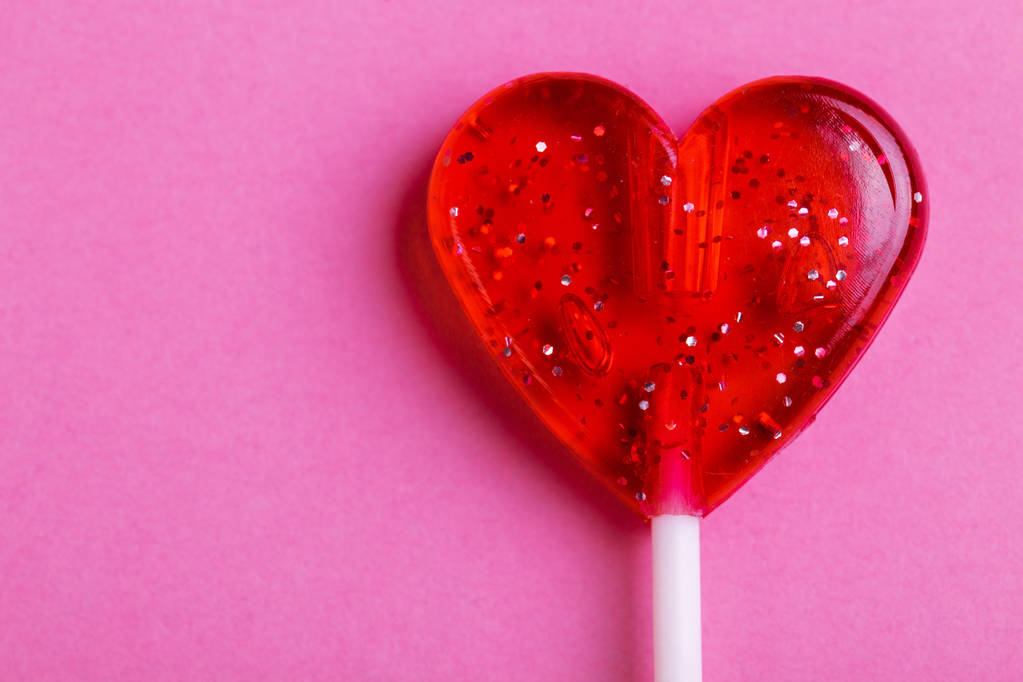 Červené sladké chutné lízátko ve tvaru srdce na světlé růžové pozadí. Den svatého Valentýna. Kopírovat prostor - Fotografie, Obrázek