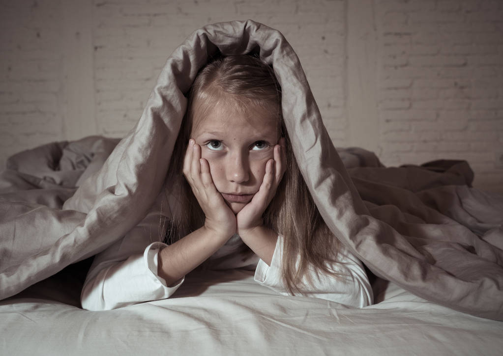 Carino piccola ragazza caucasica sdraiata a letto che copre la testa con sensazione coperta esausto e insonne affetti da insonnia Depressione Stress nei bambini Disturbi emotivi e del sonno concetto
. - Foto, immagini
