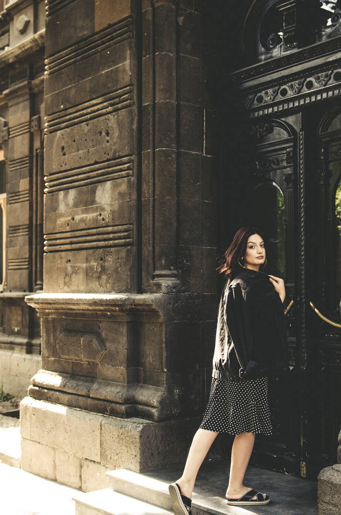 Hermosa mujer de moda en vestido negro y jeans en la ciudad
  - Foto, Imagen