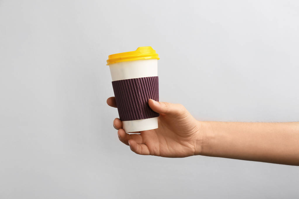 Femme tenant à emporter tasse de café en papier sur fond clair
 - Photo, image