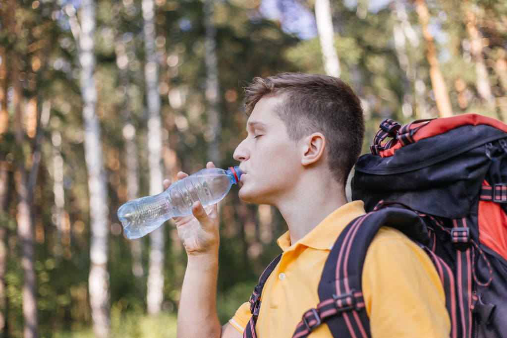 Caminante turista chico está bebiendo agua de una botella
 - Foto, imagen