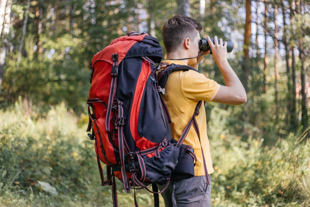 Hiker guy is looking in binoculars enjoying spectacular view - Photo, Image