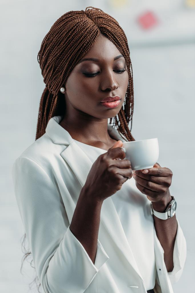 portrait de belle femme d'affaires adulte afro-américaine élégante en blanc tenant tasse de café
 - Photo, image
