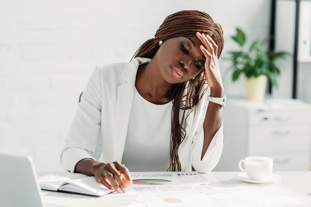 müde afrikanisch-amerikanische erwachsene Geschäftsfrau sitzt am Schreibtisch und arbeitet an einem Projekt im Büro - Foto, Bild